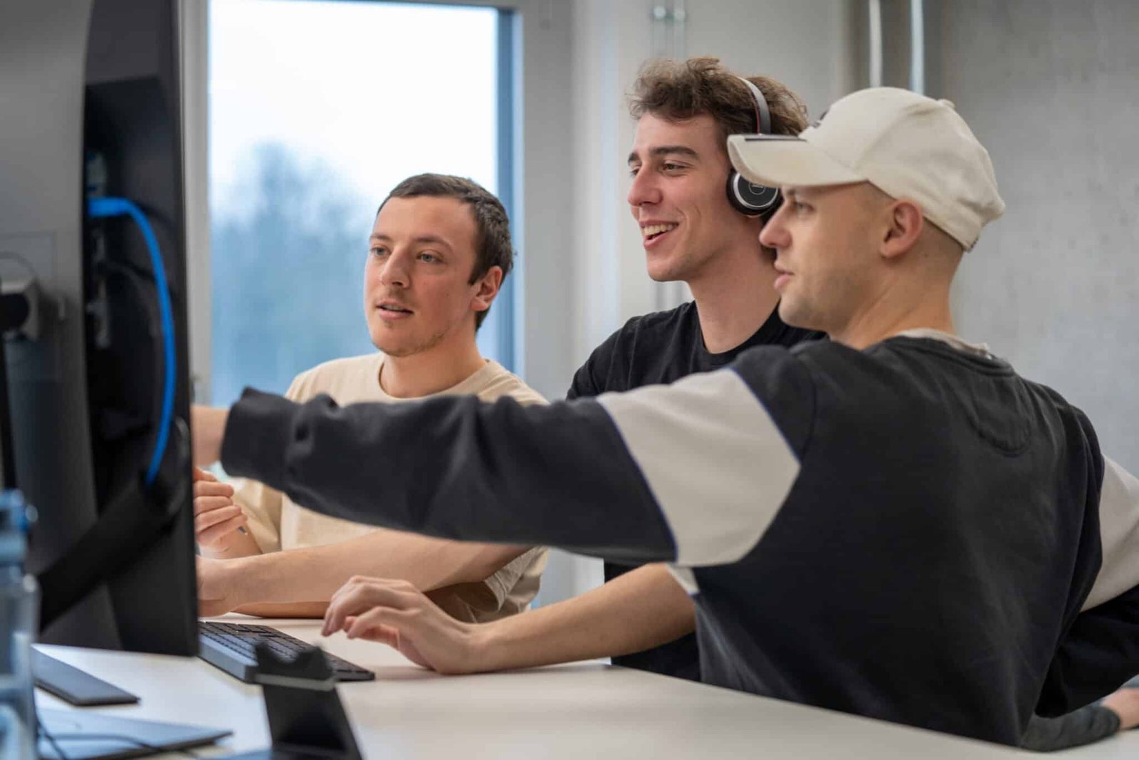 Drei Mitglieder des myls Teams arbeiten gemeinsam an einem Bildschirm